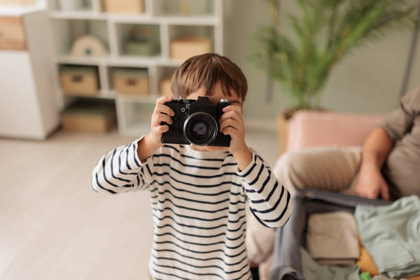 A little Caucasian boy playing with a film camera in the living room of the apartment he lives in