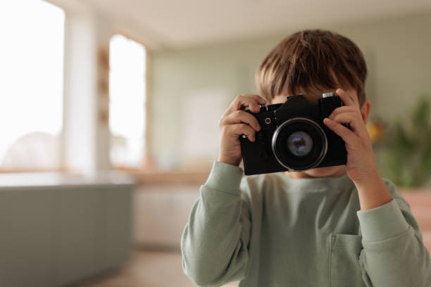 A little Caucasian boy playing with a film camera in the living room of the apartment he lives in