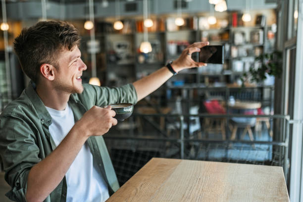 Young man sitting in modern bookstore ,library making selfie