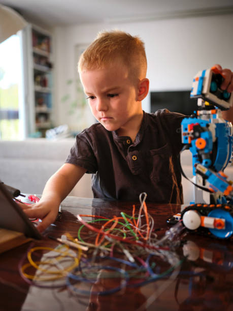 istock A young boy is seen working on a project involving a robot and several wires, capturing a sense of concentration and hands-on learning in a well-lit indoor space. 2167037364
