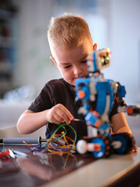 istock A young boy focused on assembling a colorful robot with various wires at play, capturing a moment of concentration and creativity in a well-lit indoor setting. 2167037497