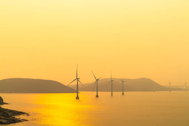 Sunset on the beach with offshore wind power generators visible on the horizon. wind force, Offshore Wind Power
