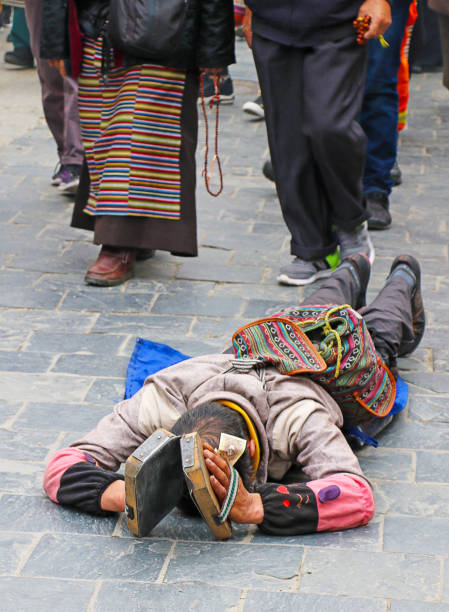 Lhasa, Tibet, China - July 12, 2017.  The photo was taken on the Tibetan plateau, in Lhasa, and specifically in Barkhor Street, along the kora of the Jokhang Temple. It shows a  pilgrim’s prayer, consisting traditionally of continuous, full body, prostrations on the ground.