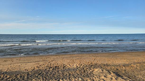 istock Serene beach scene with gentle waves lapping against the shore under a blue sky 2167043043