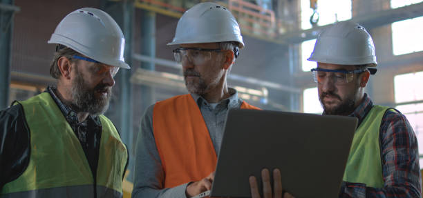 istock Three industry technicians talk about production, use laptop in factory 2167066869