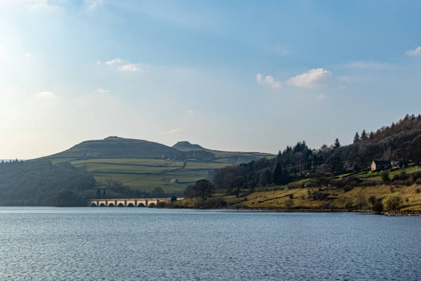 istock Serene lake with rolling hills in the background and clear blue sky. 2167067491