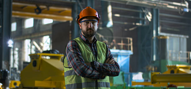 istock Heavy industry worker stands at manufacturing facility and looks at camera 2167067598