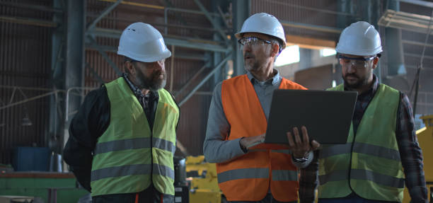 istock Three industry technicians talk about production, use laptop in factory 2167067913