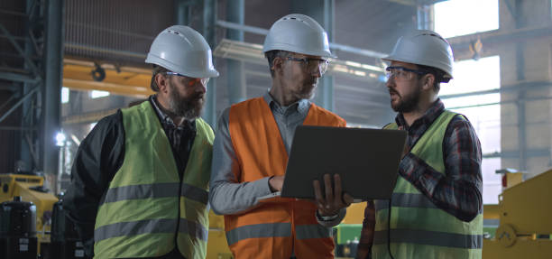 istock Three industry technicians talk about production, use laptop in factory 2167068009