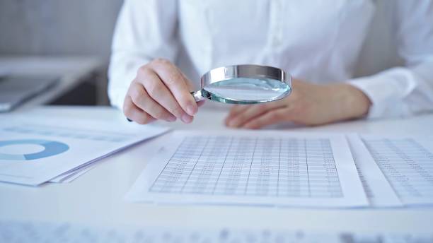istock Businesswoman with white blues is analyzing financial data on a spreadsheet using a magnifying glass. Audit and taxes 2167070762