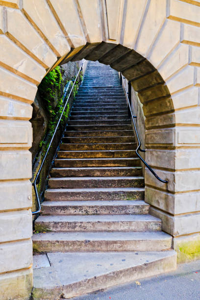 Prague, Czech republic - May 5, 2025: Two staircases with black metal railings converge towards stone wall featuring a decorative circular window, creating a symmetrical architectural scene in prague
