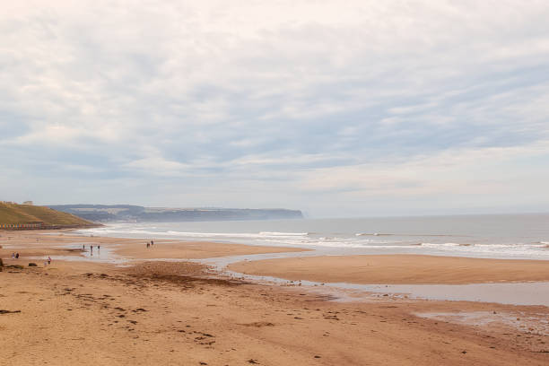 istock Overcast day at a serene beach with distant cliffs in Whitby, North Yorkshire 2167073552