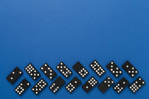 Black domino tiles on color background, top view