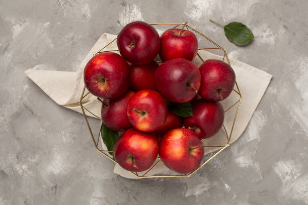 istock Fresh red apples with leaves on concrete background, top view 2167075133