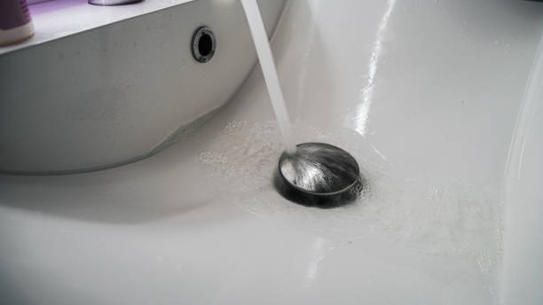 istock Clean bathroom sink with water pouring down on chrome stopper 2167077810