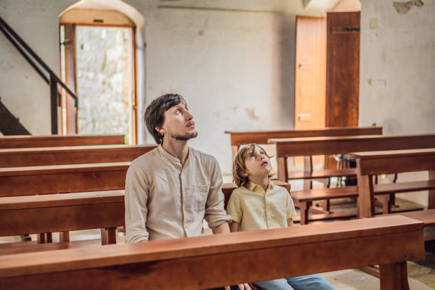 Christian dad tells his son Bible stories about Jesus sitting in kirk. Faith, religious education, modern church, father day, fatherly responsibilities, father influence on formation of son worldview. un padre cristiano le cuenta a su hijo historias bíblicas sobre jesús sentado en la iglesia. fe, educación religiosa, iglesia moderna, día del padre, responsabilidades paternales, influencia del padre en la formación de la cosmovisión del hijo