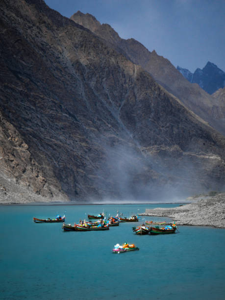 Nestled amidst the rugged mountains, this serene lake offers a breathtaking view of nature’s splendor. The vivid blue waters mirror the towering peaks, creating a harmonious blend of colors and textures. A cluster of colorful boats adds a touch of vibrancy to the tranquil scene, inviting you to explore the calm waters. The light mist hovering above the lake enhances its ethereal beauty, making it a perfect spot for reflection and peace