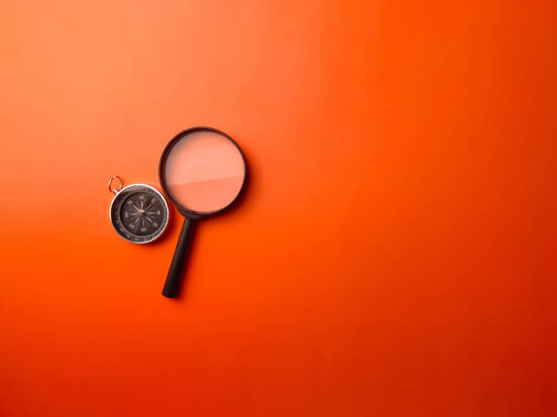 istock Top view compass and magnifying glass on a orange background 2167097977