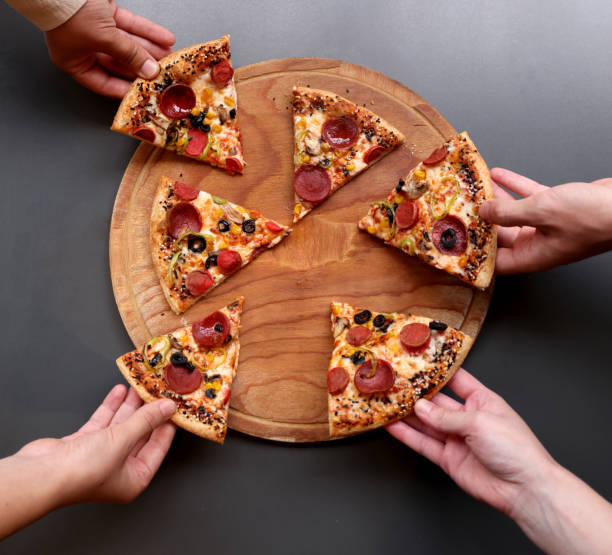 istock Young friends sharing pizza, each taking a slice 2167107428