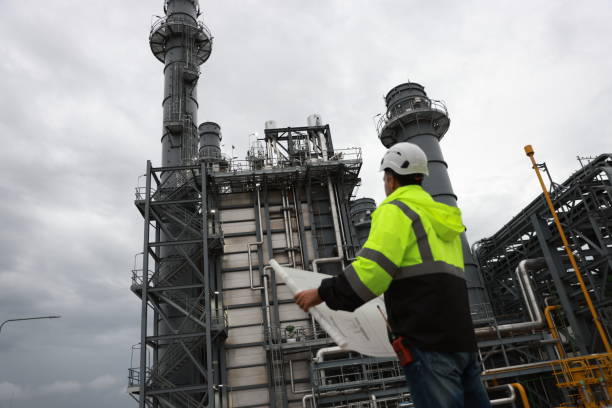istock Power plant engineer with glow green safety jacket and PPE work check drawing at the manufacturing site of a thermal power plant 2167108674