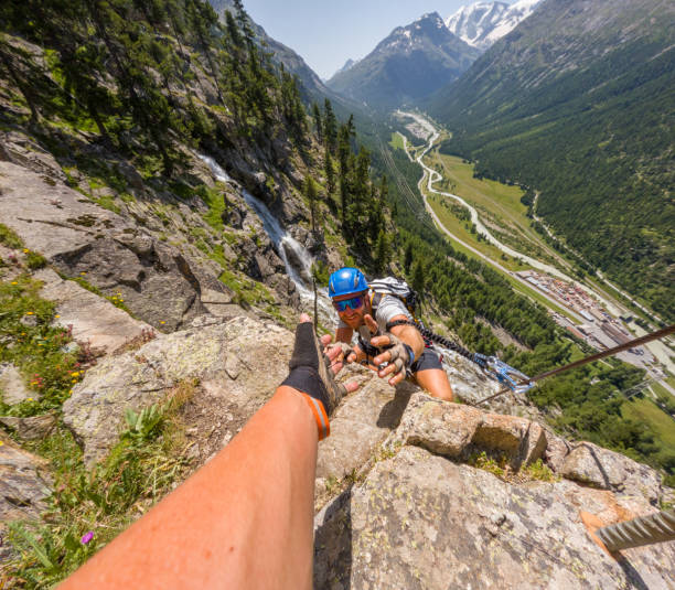 istock Climber Receiving a Helping Hand While Scaling a Steep Cliff 2167109249