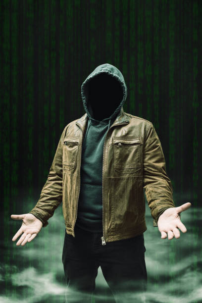istock Faceless man, hooded cybercriminal terrorist, anonymous hacker standing on a dark green background with a smoke 2167112632