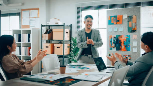 Creative team reviewing and discussing mobile app interface designs in a modern office. Group collaboration on digital project with design prototypes.