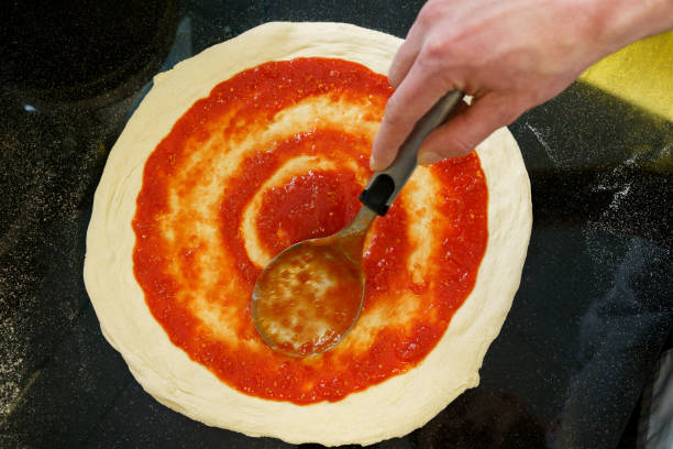 istock Top down view of spreading tomato sauce on pizza dough with a spoon 2167123339