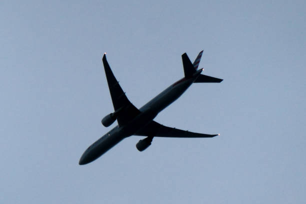 American Airlines B777 Overhead An American Airlines Boeing B777-323(ER) plane, registration N734AR, crossing the coast over Bondi Beach at about 6,000 feet as she prepares to land at Sydney Kingsford-Smith Airport as flight AA73 from Los Angeles. This image was taken from Bondi Beach on an overcast morning before sunrise on 17 August 2024. bondi beach sunrise stock pictures, royalty-free photos & images