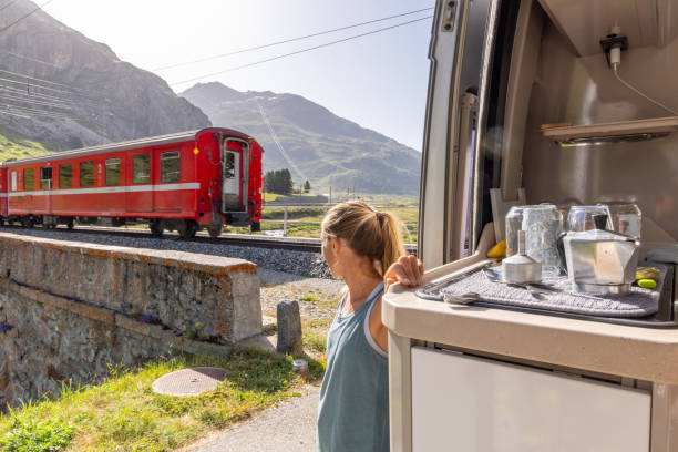 istock Woman Admiring Mountain Scenery as Train Passes by Campervan 2167129526
