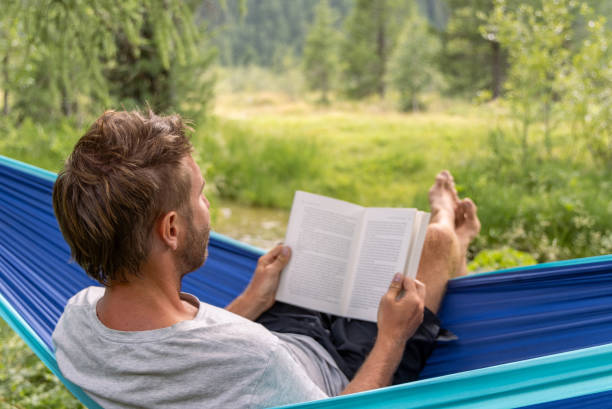 istock Man Relaxing in Hammock Reading a Book in Nature 2167131538
