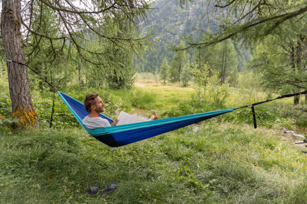 istock Man Relaxing in Hammock Reading a Book in Nature 2167131798