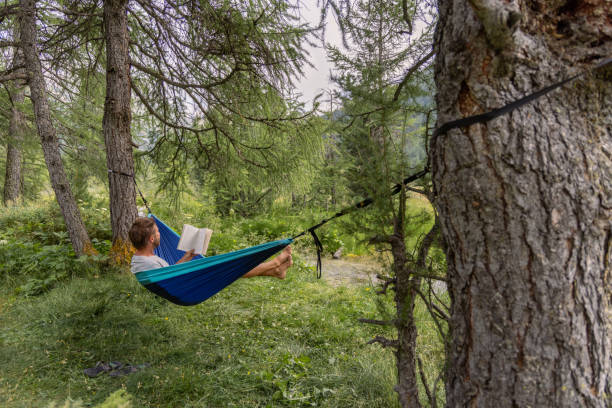 istock Man Relaxing in Hammock Reading a Book in Nature 2167131801