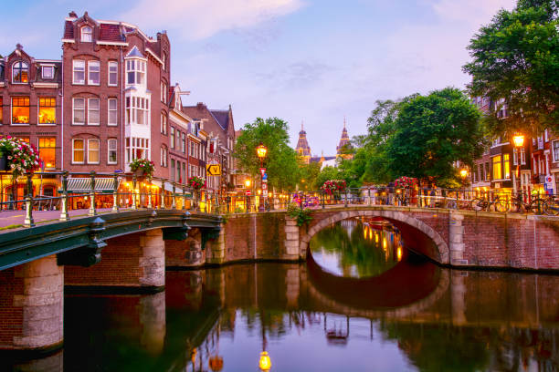 Old houses and a bridge over Amstel river in downtown of Amsterdam at night, Netherlands