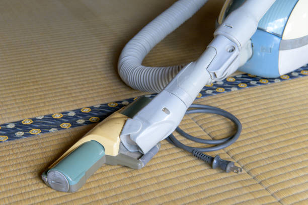 A person is actively utilizing a vacuum cleaner in order to effectively clean a wall surface within their home environment