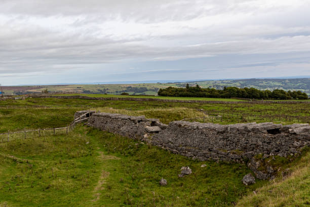 istock Rural landscape with stone walls and green fields under a cloudy sky. 2167139392