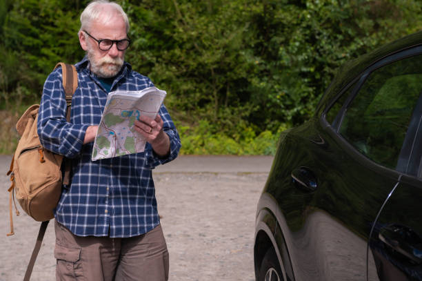 istock Senior man standing beside his car looking at a map 2167145618