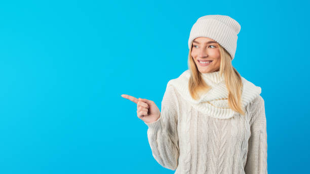 istock Woman in White Sweater and Hat Pointing at Copy Space 2167146226