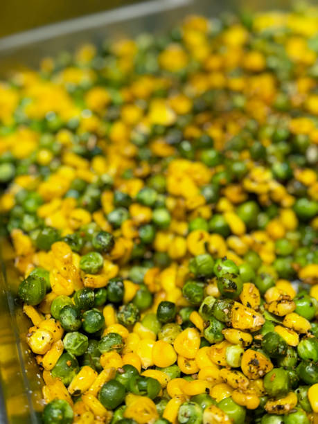 Stock photo showing close-up, elevated view of a pile of freshly cooked, seasoned sweetcorn and green peas in a metal serving tray as part of a hotel self service buffet.
* Not AI modified * imagen en primer plano de una pila mixta de maíz dulce sazonado (zea mays convar. saccharata var. rugosa) y guisantes verdes (pisum sativum) en una bandeja de metal para servir, recién cocinado, comida servida en el buffet de autoservicio del hotel, vist