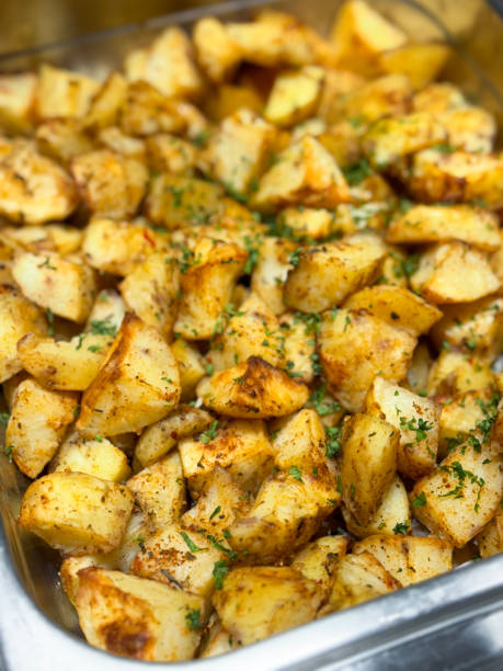 istock Full frame image of metal serving tray containing freshly cooked, diced, herb roasted potatoes, pile of crunchy herb and spice coated potatoes, food being served at hotel self service buffet, elevated view, focus on foreground 2167146663