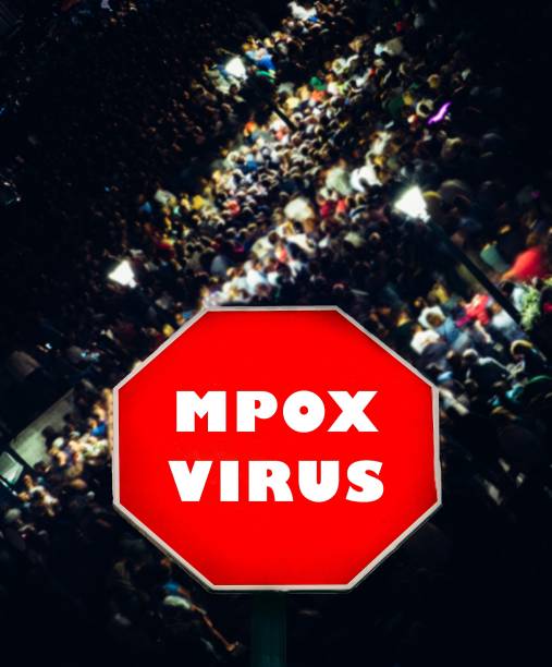 istock Urban crowd gathered under a warning sign about mpox virus during a nighttime event 2167150038