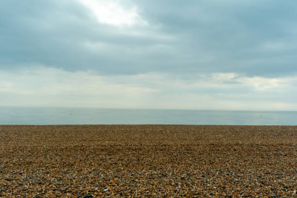 Pebble beach with overcast sky, tranquil sea horizon, and ample copy space.