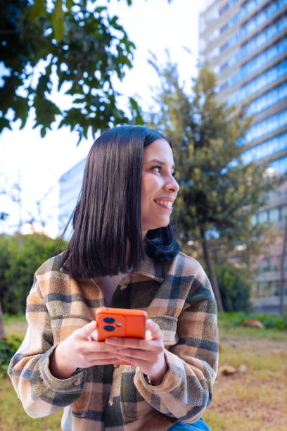 istock Vertical portrait smiling young female using smartphone app outdoors. 2167159527
