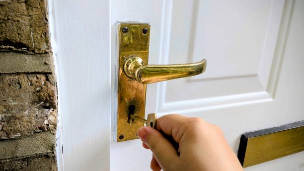 istock Opening an old white door with a golden key 2167162152