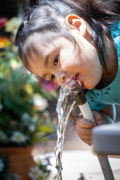 istock A young girl is drinking water from a hose 2167162194