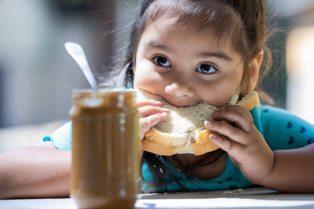A young girl is eating a peanut butter sandwich