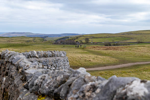 istock Rustic stone wall with a blurred background of rolling green hills and a clear sky, depicting tranquil rural landscape in Peak District, England. 2167171301