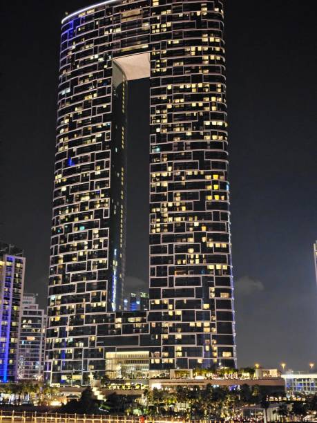 istock Modern skyscraper with a unique cutout design illuminated at night in a bustling urban area 2167174642