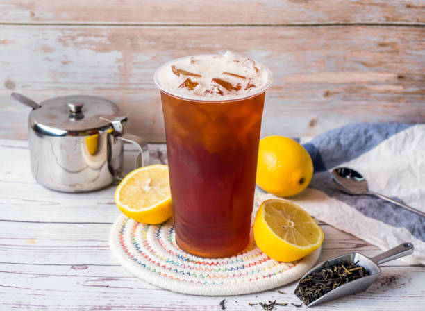 Iced lemon black tea with sugar pot and spoon served in disposable glass isolated on table side view of hong kong tea