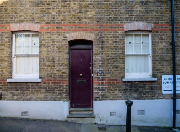The colorful pastel facade and forest green front door of a traditional terraced London mews townhouse.